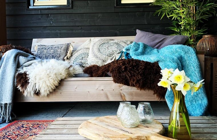 Stylish sitting area on the veranda of Holiday Home in Oosterend, Texel, with soft blankets and pillows.