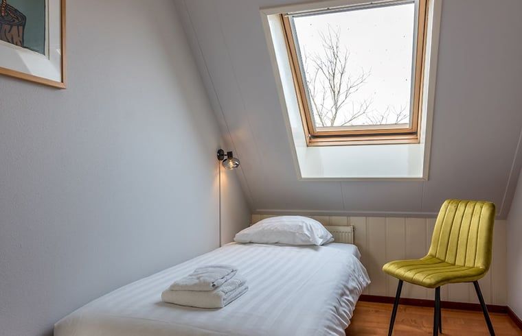 Einzelzimmer im Ferienhaus in Oosterend, Texel, Ferienhaus mit Dachfenster und Stuhl auf den Watteninseln.