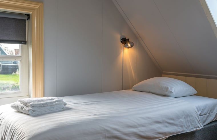 Cozy bedroom with single bed and reading lamp in Holiday cottage in Oosterend, Texel.