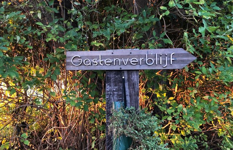 Wooden sign points to guesthouse at Holiday home in Oosterend, Texel. Cozy vacation home on the Wadden Islands.