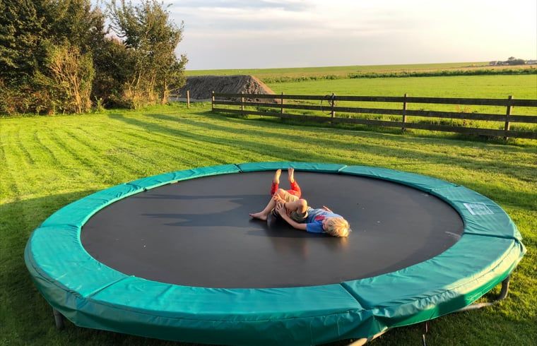 Children play on trampoline in garden of Holiday home in Oosterend, Texel. Family-friendly vacation home on the Wadden Islands.