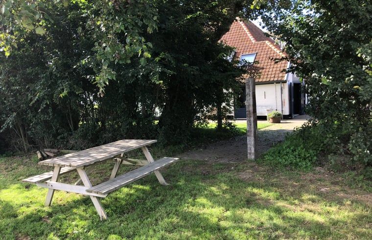 Picnic table under trees at Holiday home in Oosterend, Texel. Shady vacation home in the Wadden Islands.
