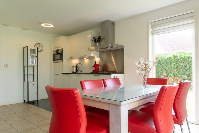 Esszimmer und Kueche in Typ II+ - Nr. 77 Goldfinch, Ferienhaus in Oosterend Texel mit roten Stuehlen.