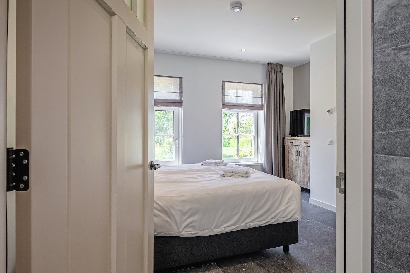 Ruime slaapkamer met rode accentmuur in vakantiehuis 46 - Nieuw Zeeland, Oosterend, Texel.