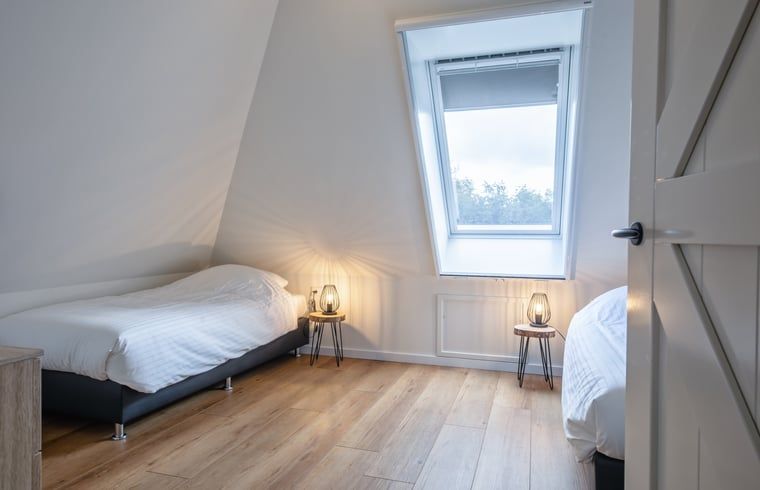 Zweites Schlafzimmer im Ferienhaus in Oudeschild, Texel, mit zwei Einzelbetten und stimmungsvoller Beleuchtung.