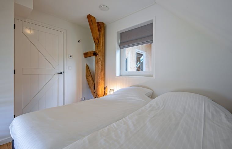 Gemuetliches Schlafzimmer im Ferienhaus in Oudeschild, Ferienhaus Texel, mit Holzbalken und Fenster.