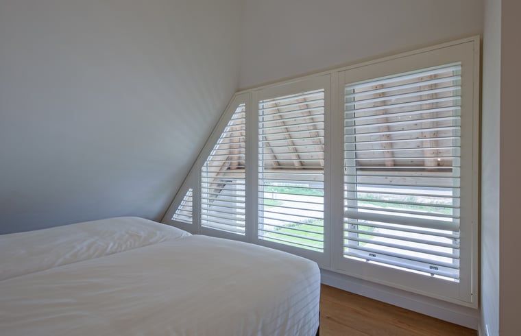 Schlafzimmer mit Aussicht im Ferienhaus in Oudeschild, Texel, mit bequemen Betten und Fensterlaeden.