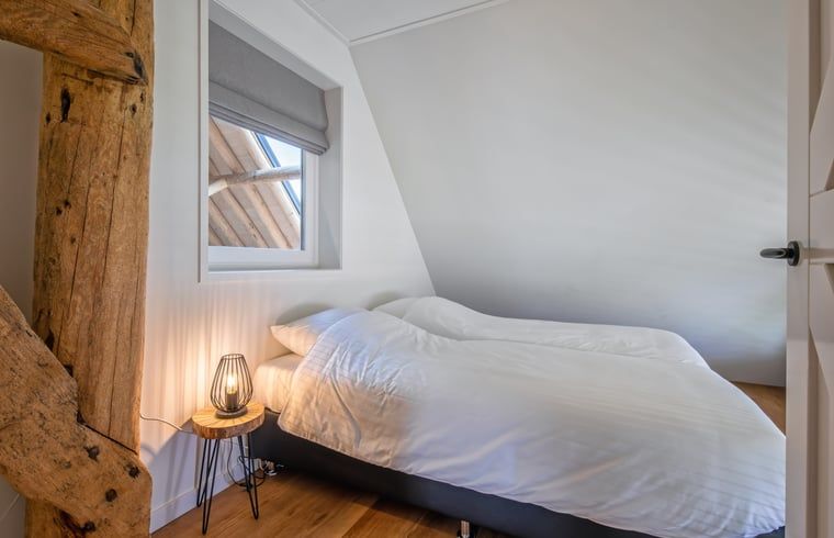 Attraktives Schlafzimmer in einem Ferienhaus in Oudeschild, Texel, mit Holzelementen und Nachtlicht.