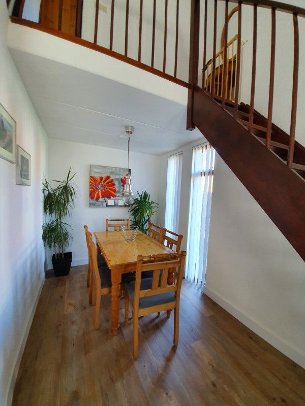 Dining area with wooden table in Alkema bungalow rental Gortersmient, Texel with art on the wall.