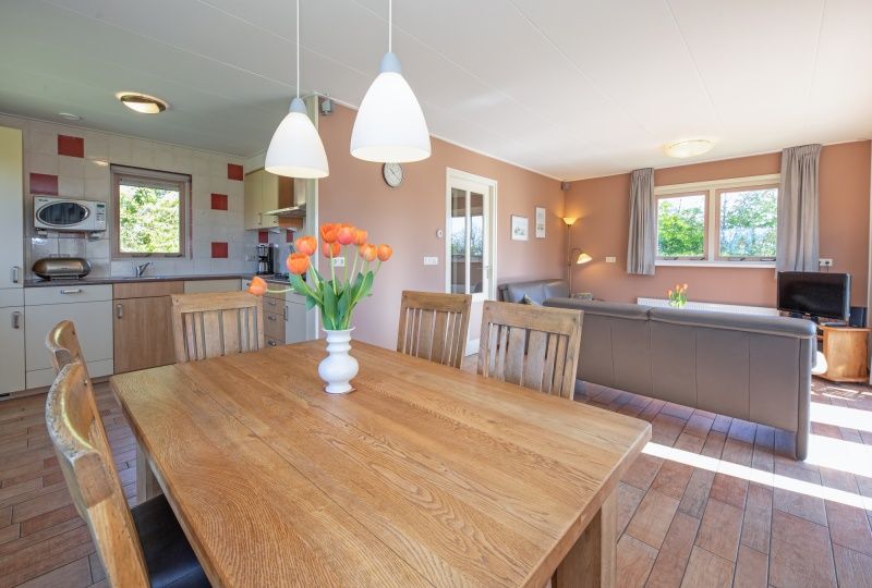 Eethoek in 8690 - Junier - Huisman vakantiehuis, Zuid-Eierland, Texel, met houten tafel en uitzicht op de natuur.