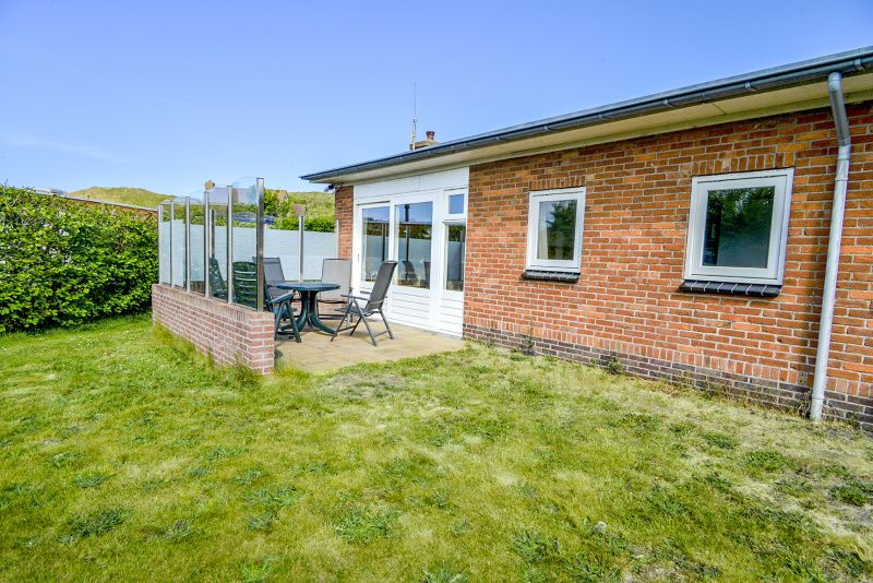 Veranda van Slufterbungalows 362 in Bungalowpark Slufteroord, Texel met zitgelegenheid en groen uitzicht.