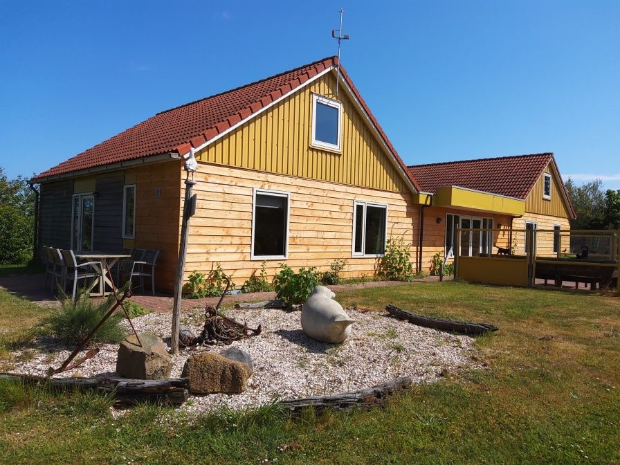 De Triaan vakantiewoningen in Zuid-Eierland, Texel, offers a charming vacation home with wooden facade and spacious garden.