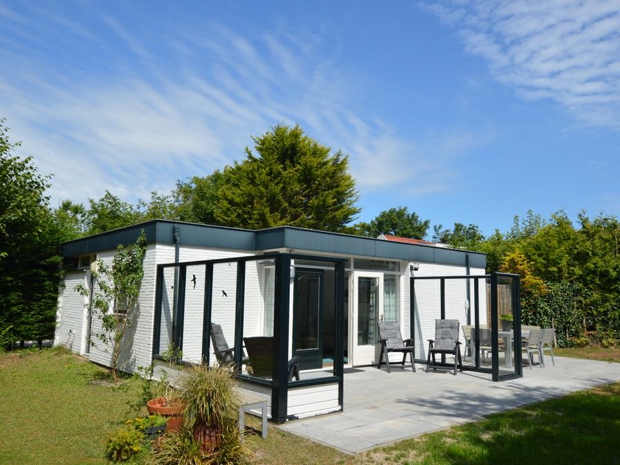 Ferienhaus de Parel 182 in De Dennen, Texel mit sonniger Terrasse und gruener Umgebung.