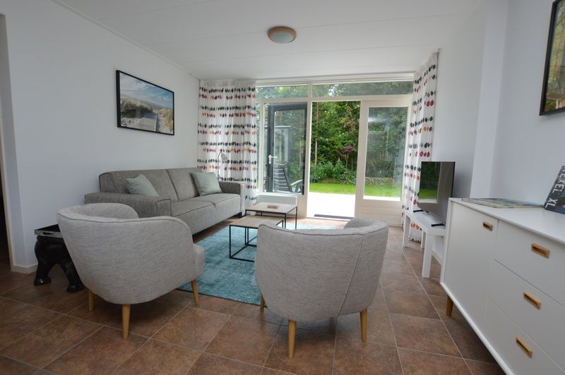 Gemuetliches Wohnzimmer des Ferienhauses de Parel 182 in De Dennen, Texel mit Blick auf den Garten.