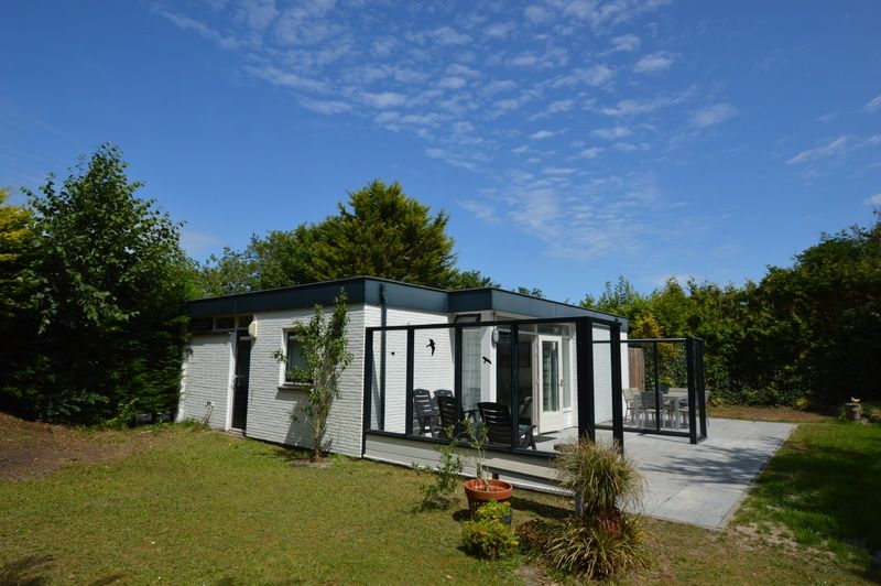 Aussenansicht des Ferienhauses de Parel 182 in De Dennen, Texel mit Terrasse und gruenem Garten.