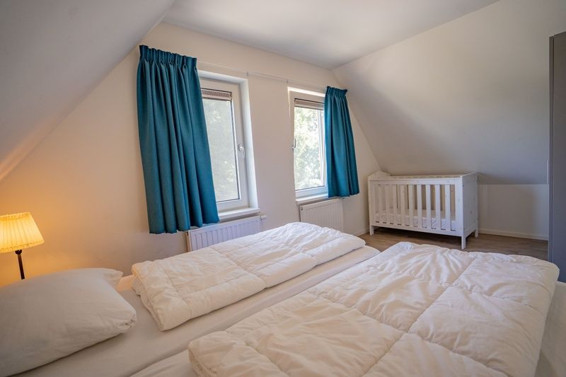 Geraeumiges Schlafzimmer mit Kinderbett im Ferienhaus de Parel 150, De Dennen, Texel.