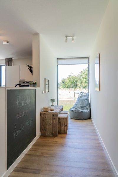 Entrance hall of Holiday Home 2 in De Dennen, Texel with wooden bench and garden view.