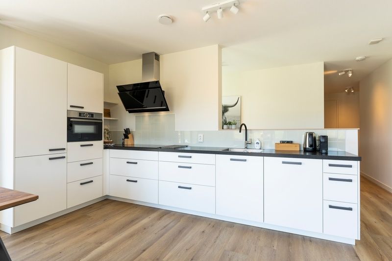 Modern kitchen of Holiday Home 2 on Texel with white cabinets and black accents.