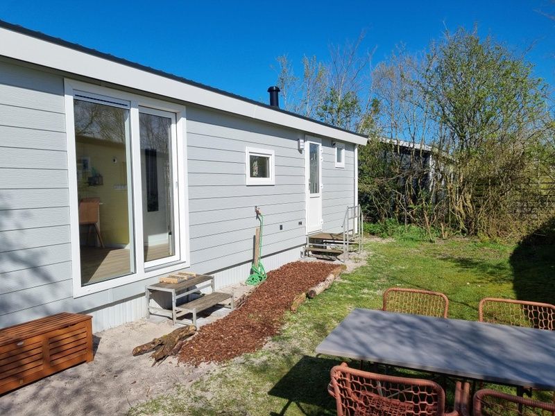 Seitenansicht von Vakantiepark de Bremakker - Bosveld 135, Ferienhaus in De Dennen, Texel mit Terrasse und Gartenmoebeln.