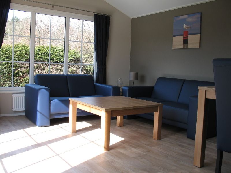 Helles Wohnzimmer von Villetta Sauna, Texel, mit bequemen Sofas und Blick auf die Natur.