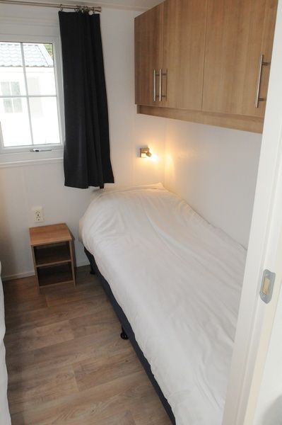 Gemuetliches Einzelzimmer in Villetta Sauna, De Dennen, Texel mit Holzschrank und Fenster.