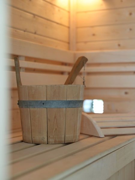 Detail der Sauna in Villetta Sauna, Texel, mit Holzkuebel und warmer Beleuchtung.
