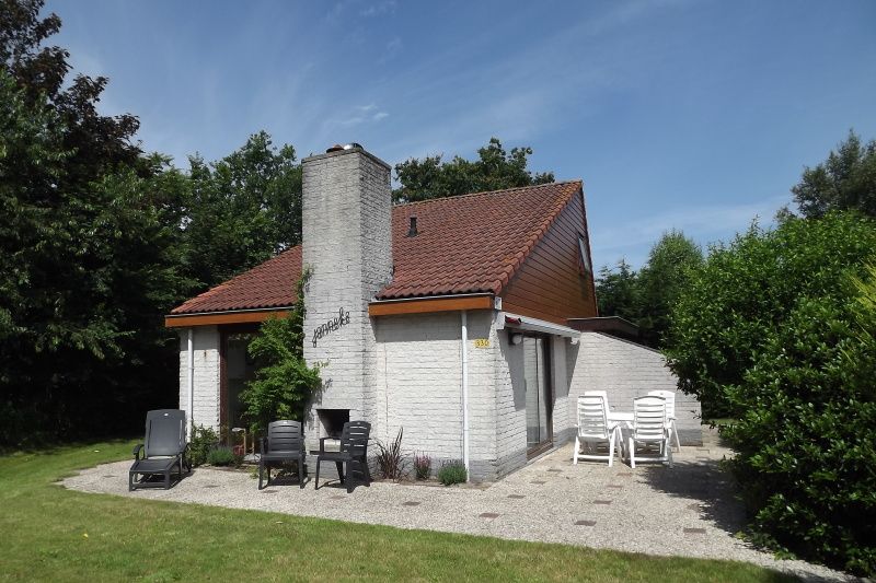 Aussenansicht des Ferienhauses Gortersmient 330, De Dennen, Texel mit Terrassenstuehlen.