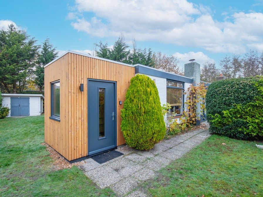 Bungalowpark 't Luwe Land - 7B - De Wijnhof, Ferienhaus in De Dennen, Texel, mit gruenem Garten und blauem Himmel.