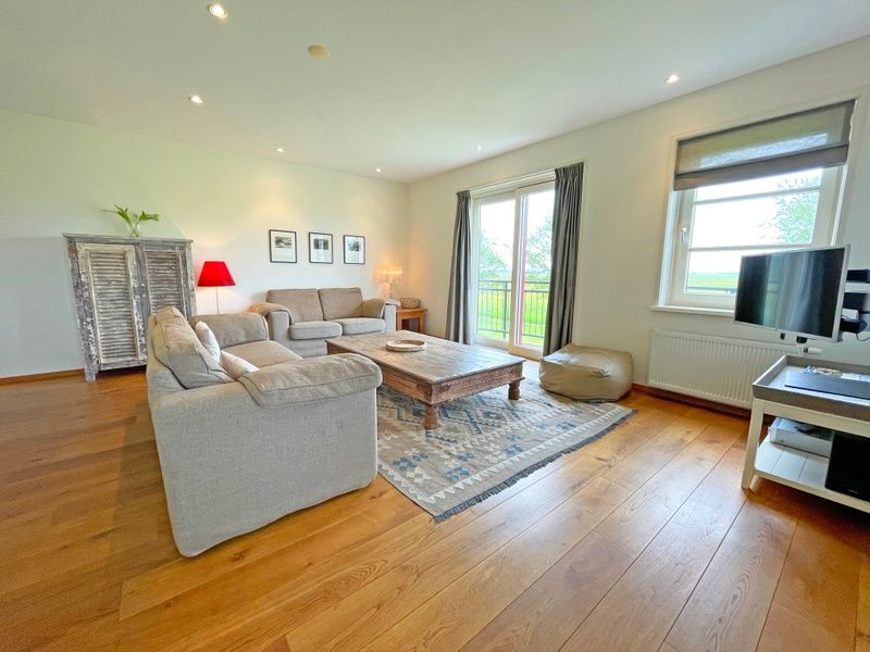 Stijlvolle zithoek in Appartement Bos en Duin 40, De Dennen, Texel, met houten vloer en moderne inrichting.