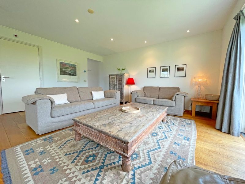 Ruime woonkamer van Appartement Bos en Duin 40, Texel, met rustieke houten tafel en sfeervolle verlichting.