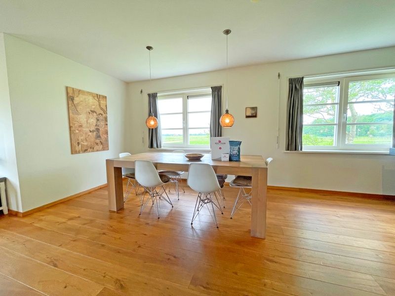 Eetkamer in Appartement Bos en Duin 40, De Dennen, Texel, met grote houten tafel en ramen met uitzicht op de natuur.