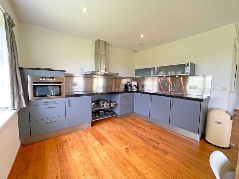 Moderne keuken van Appartement Bos en Duin 40, Texel, met roestvrijstalen apparatuur en veel werkruimte.