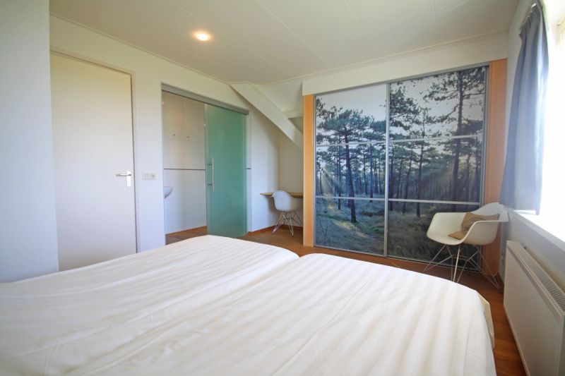 Stijlvolle slaapkamer in Appartement Bos en Duin 40, De Dennen, Texel, met tweepersoonsbed en bosdecoratie.