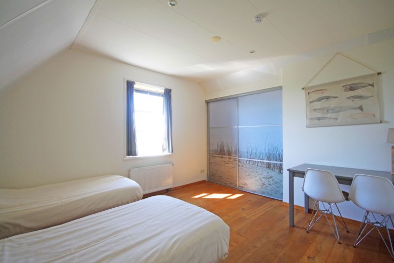 Lichte slaapkamer van Appartement Bos en Duin 40, Texel, met twee eenpersoonsbedden en strandthema.