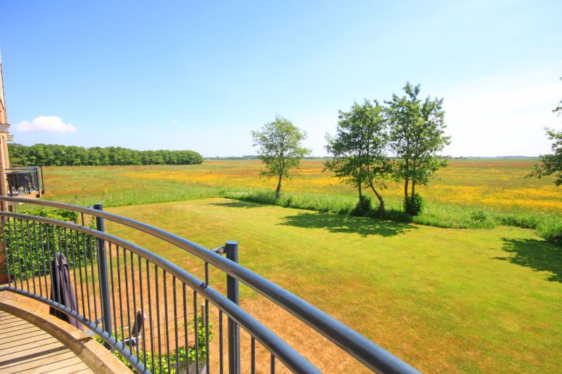 Balkon van Appartement Bos en Duin 40 in De Dennen, Texel, met uitzicht op het weidse landschap en grasvelden.