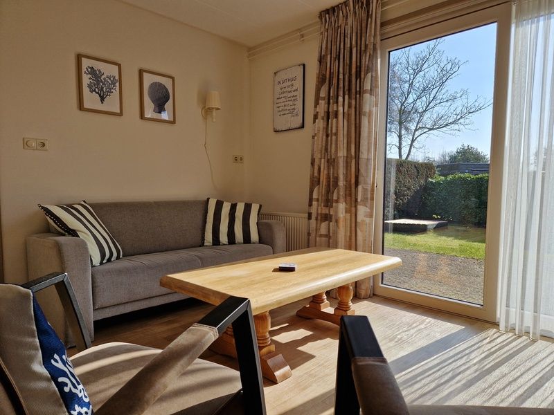 Cozy living room in Bungalowpark Uterste Coogh - Bungalow 116, De Dennen, Texel overlooking the green garden.