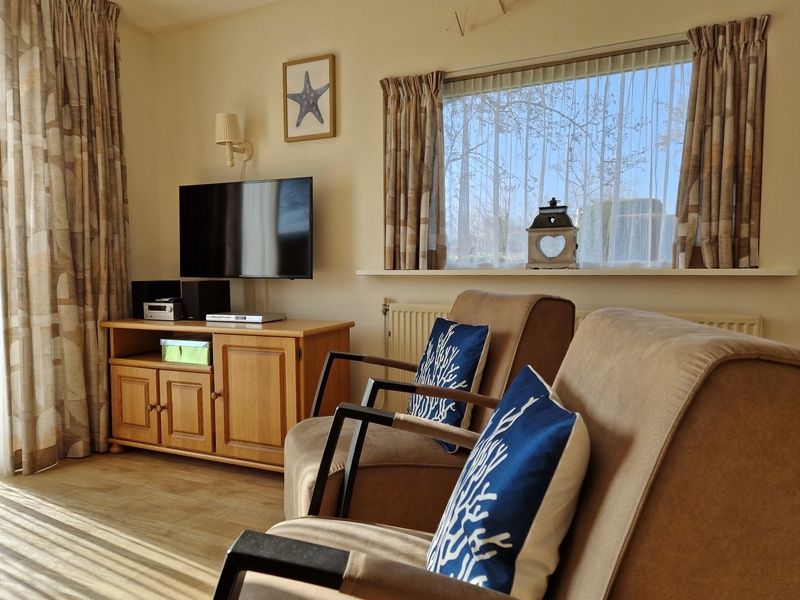 Comfortable sitting area with television in Bungalowpark Uterste Coogh - Bungalow 116, De Dennen, Texel for relaxation.
