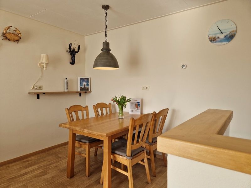 Stylish dining area in Bungalowpark Uterste Coogh - Bungalow 116, De Dennen, Texel with wooden table and chairs.