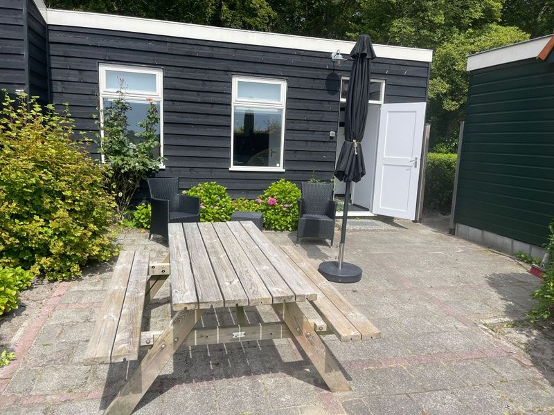 Terrace of Wollewei vacation home in De Dennen, Texel, with wooden picnic table and chairs.