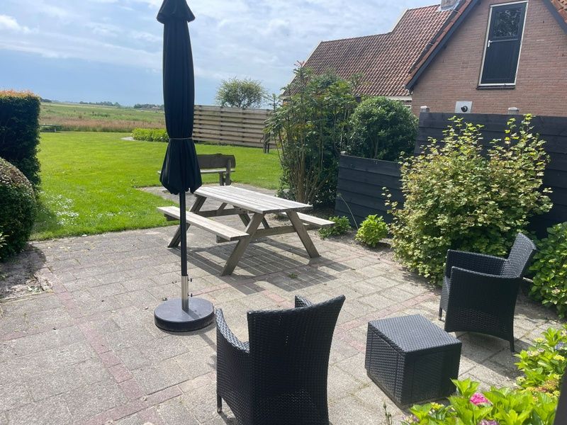 View from the terrace of Wollewei vacation home in De Dennen, Texel, with green garden.