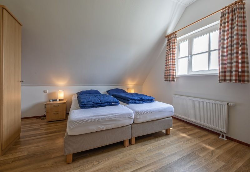 Spacious bedroom with double bed in 't Mienthuis - De Jonker, vacation home in De Dennen, Texel for a relaxing night's sleep on the Wadden Islands.
