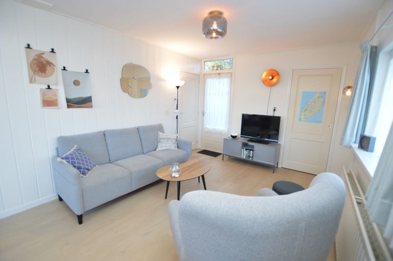 Stilvoller Wohnbereich im Ferienhaus Uterste Coogh 104, Texel, mit bequemem Sofa und Sessel.