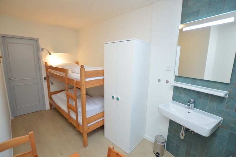 Gemuetliches Schlafzimmer im Ferienhaus Uterste Coogh 104, Texel, mit Etagenbett und Waschbecken.