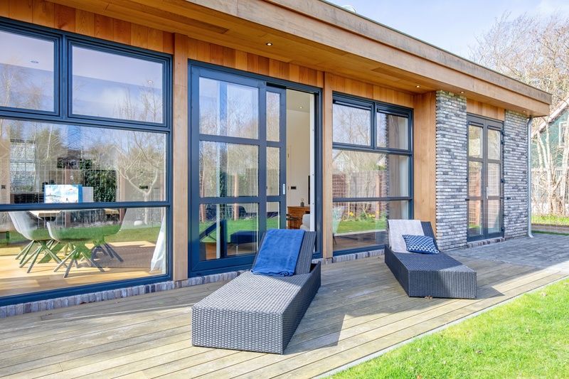 Luxe ligstoelen op het terras van Vakantiehuis De Vlinder in Bungalowpark 't Hoogelandt, De Dennen, Texel, met uitzicht op de tuin.