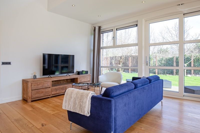 Stijlvolle woonkamer van Vakantiehuis De Vlinder in Bungalowpark 't Hoogelandt, Texel, met uitzicht op de groene omgeving van De Dennen.