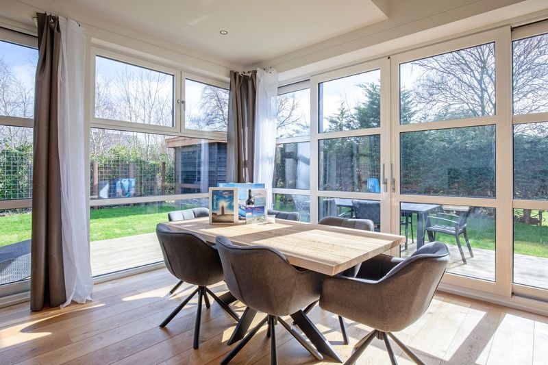 Eethoek met uitzicht op de tuin in Vakantiehuis De Vlinder, Bungalowpark 't Hoogelandt, De Dennen, Texel, voor een ontspannen verblijf.