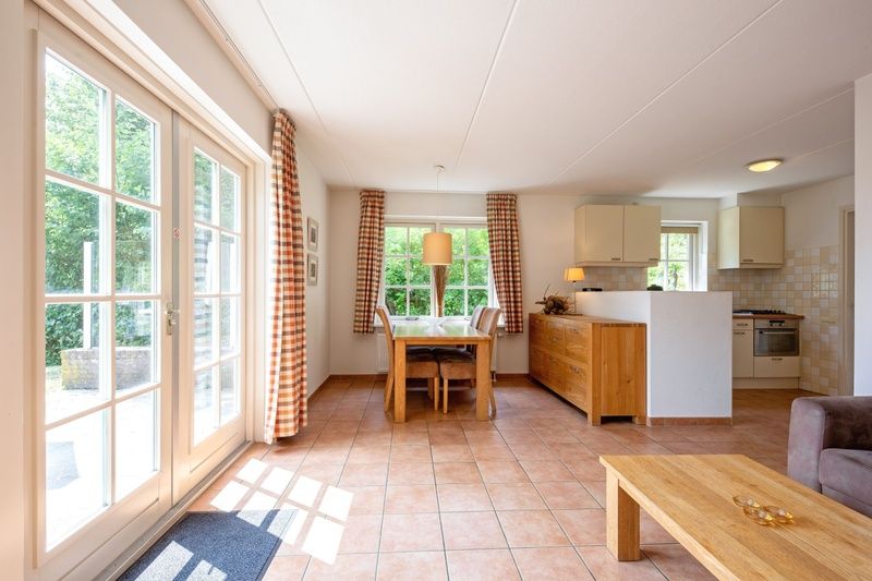 Esszimmer und Kueche in 't Mienthuis - De Prins, Ferienhaus in De Dennen, Texel, mit grossen Fenstern und Holzmoebeln.