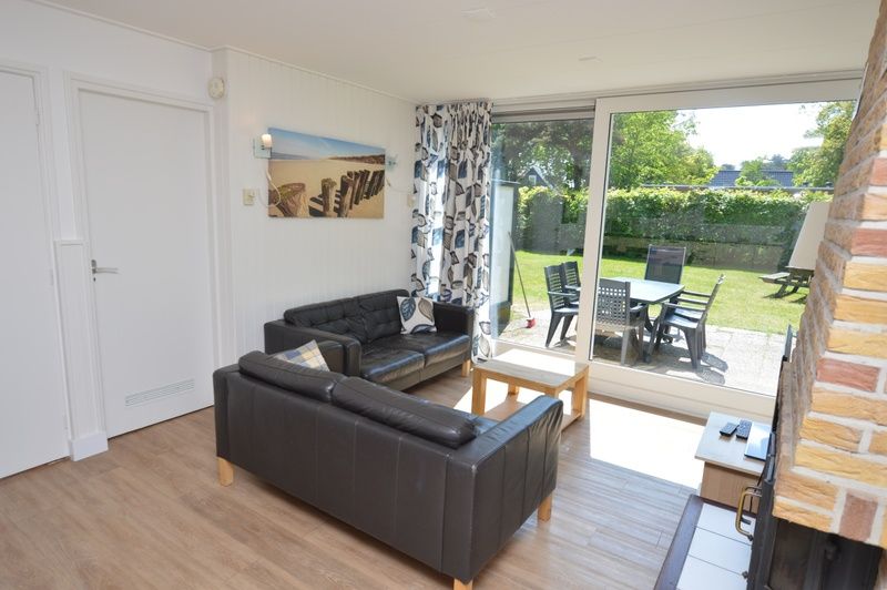 Helle Innenraeume im Ferienhaus de Parel 282, De Dennen, Texel mit gemuetlicher Sitzecke und Gartenblick.