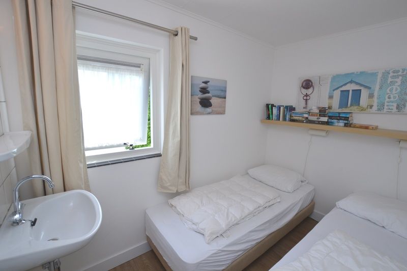 Zweites Schlafzimmer im Ferienhaus de Parel 282, De Dennen, Texel mit zwei Einzelbetten und Buecherregal.