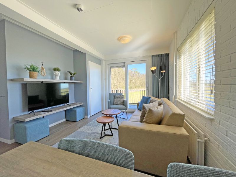 Stijlvolle woonkamer van Appartement Bos en Duin 30, De Dennen, Texel met uitzicht op het groene landschap.